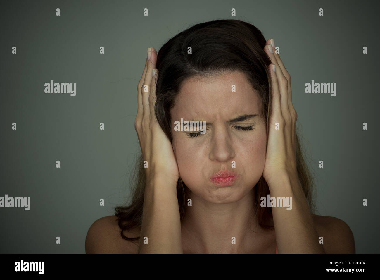 Woman holding hands over ears with eyes closed Stock Photo