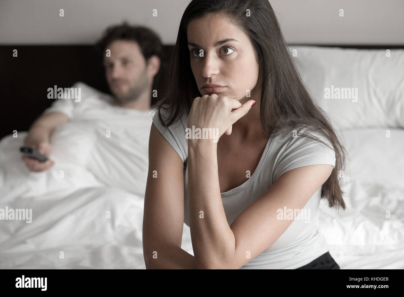 Woman sitting in bed while husband watching tv Stock Photo