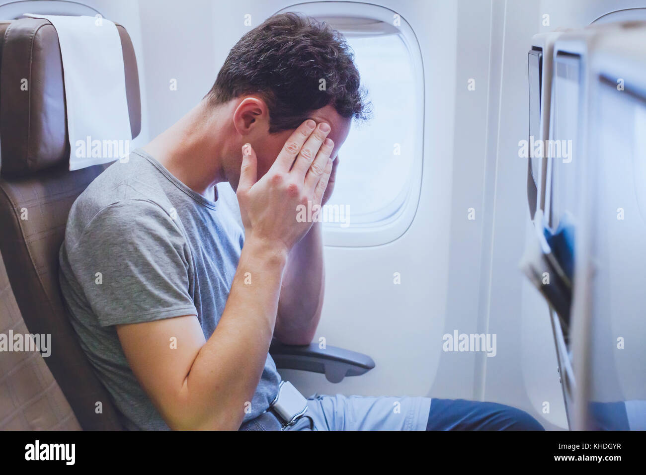 headache in the airplane, man passenger afraid and feeling bad during the flight in plane Stock Photo