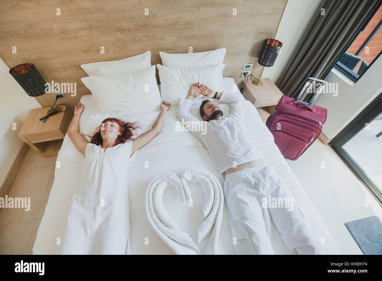 happy couple in luxury hotel room, holidays travel accommodation, top view of smiling man and woman lying down on the bed Stock Photo