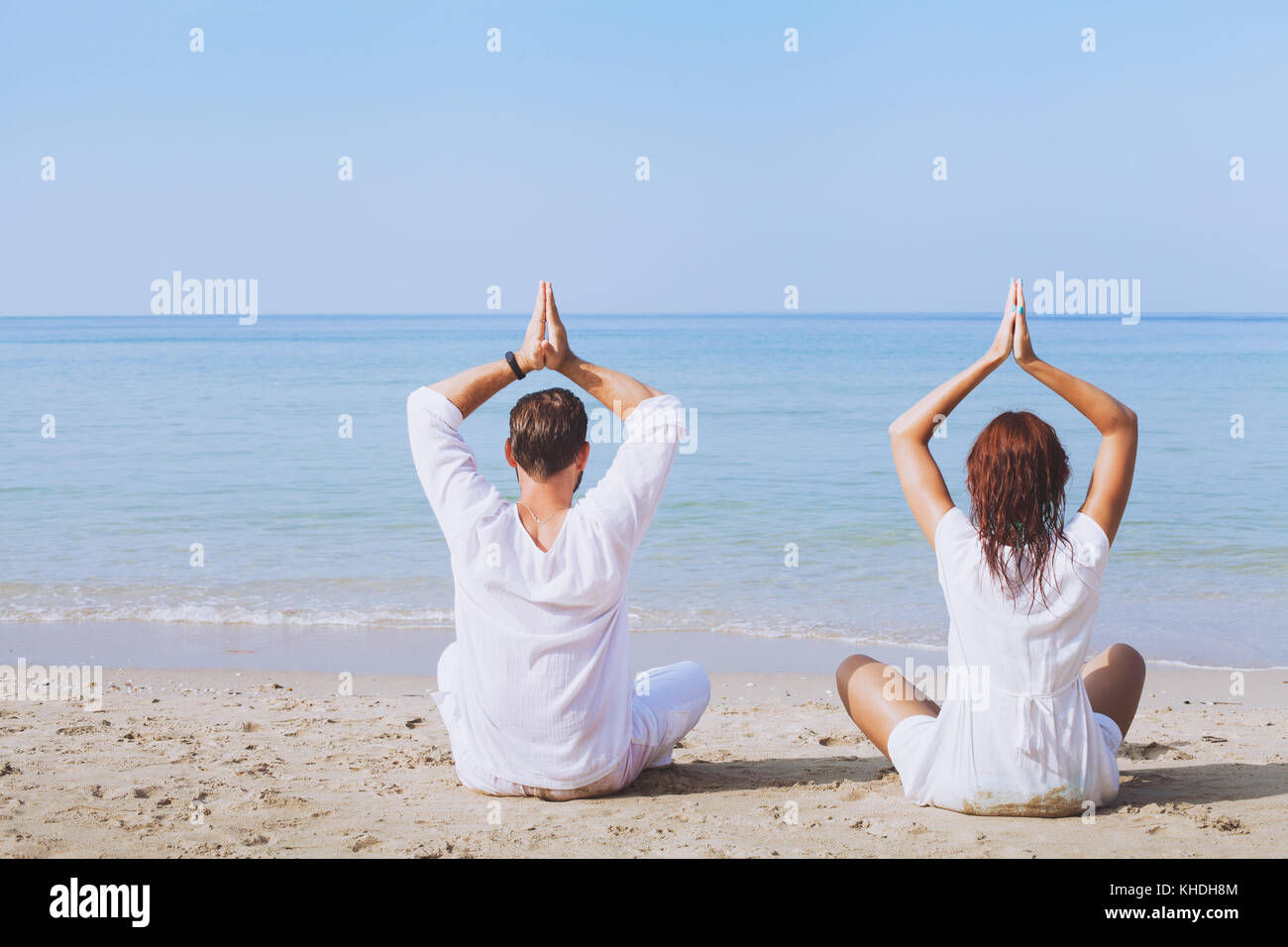 yoga on the beach, two people in white clothes practicing meditation, healthy lifestyle background Stock Photo