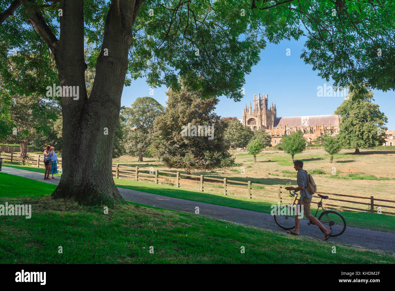 Ely city view, a young cyclist pushes his bike along a path in Cherry