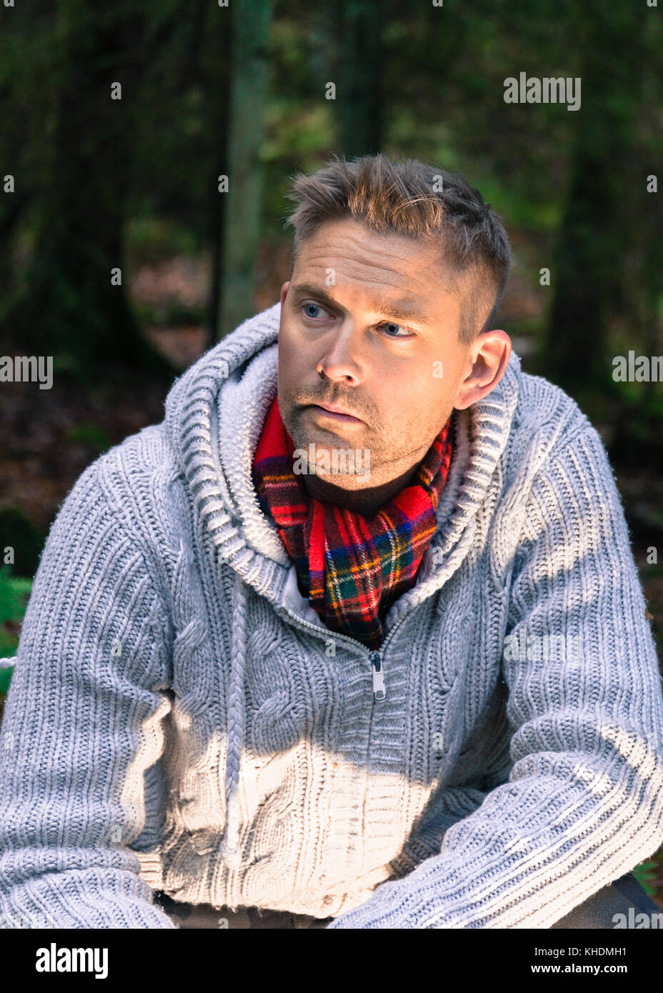 Mid adult man in woods lifestyle portrait wearing knitted jumper and red scarf looking away  Model Release: Yes.  Property Release: No. Stock Photo