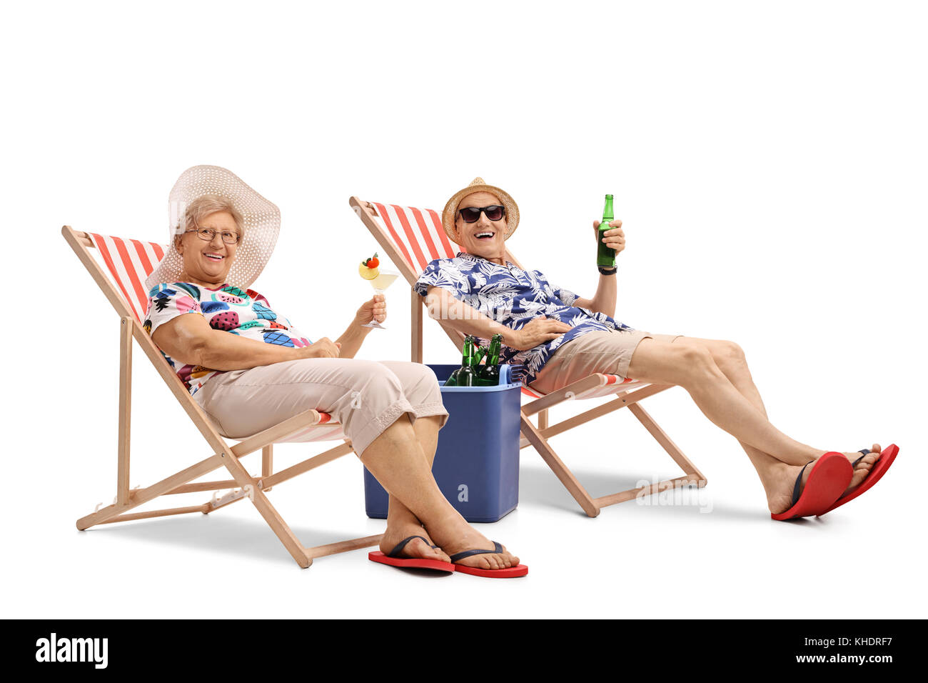 Happy elderly tourists with a cocktail and a bottle of beer seated in deck chairs isolated on white background Stock Photo