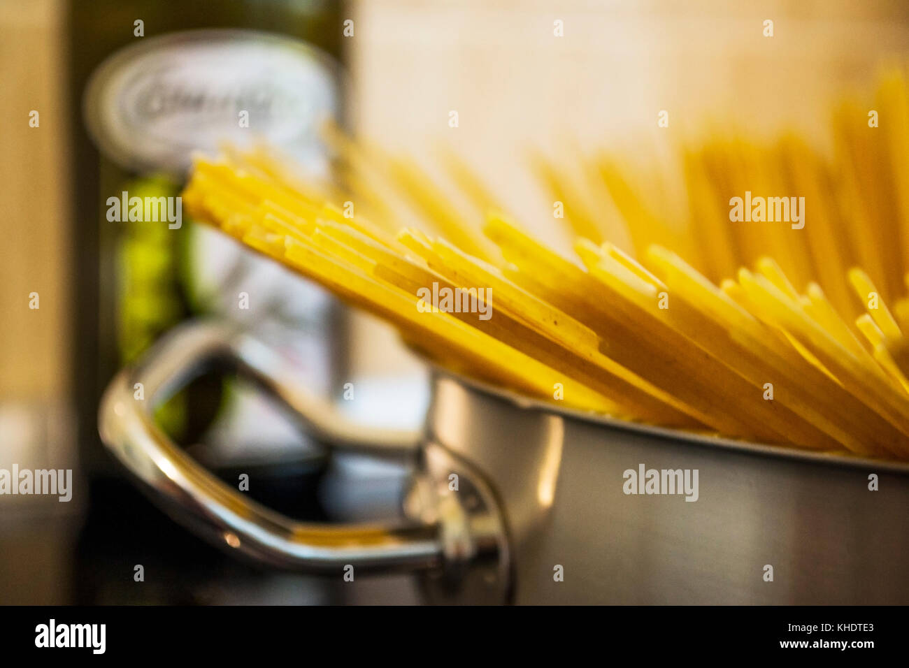 Spaghetti in a pot just starting to boil, with an olive oil bottle in