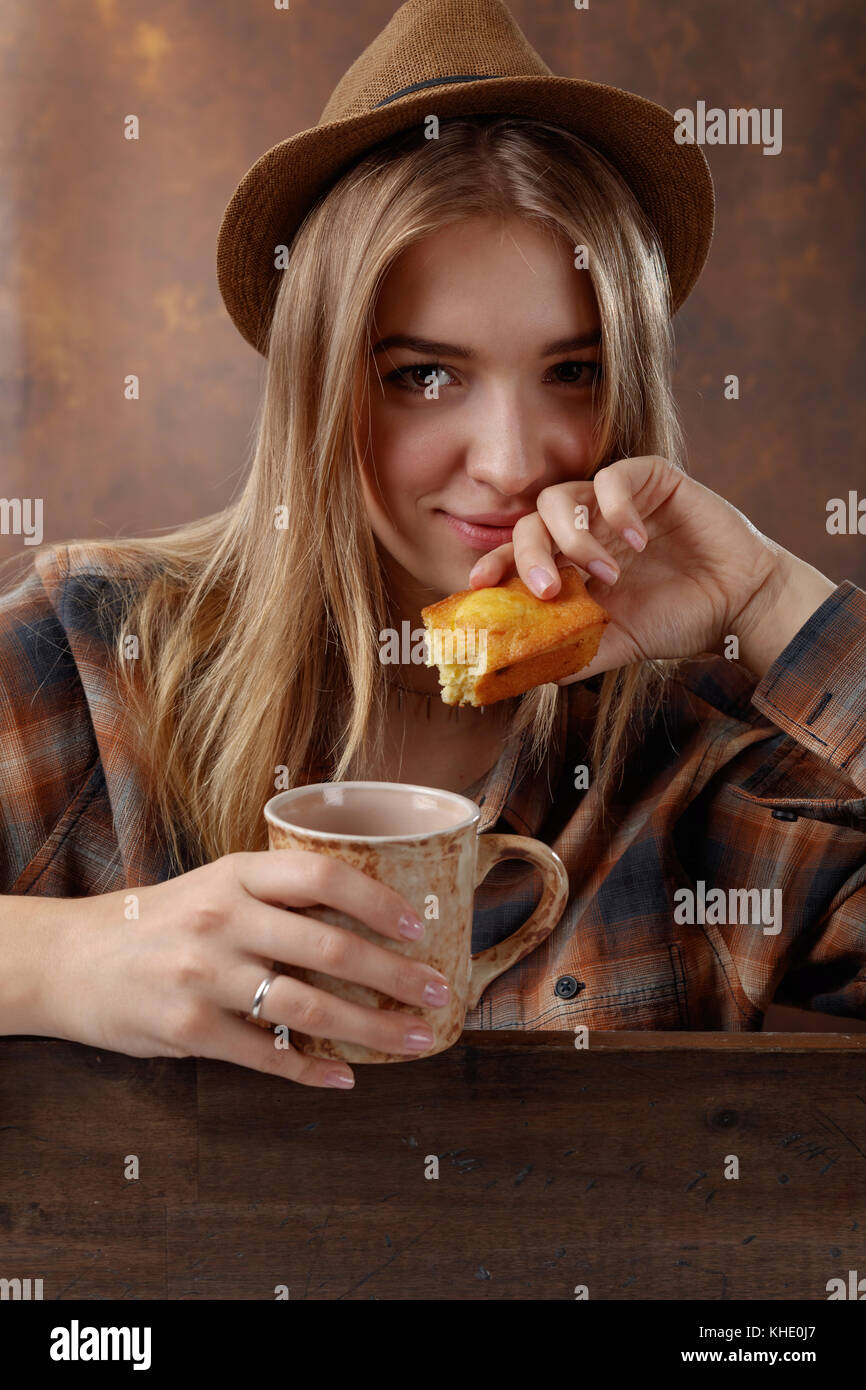 Young beautiful blonde in a brown plaid shirt with a mug of coffee and