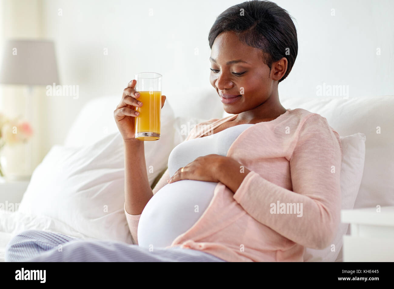 pregnant woman drinking orange juice in bed Stock Photo Alamy