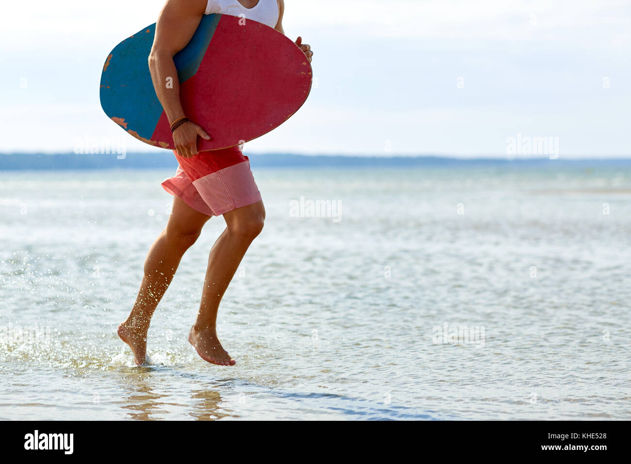 young man with skimboard on summer beach Stock Photo