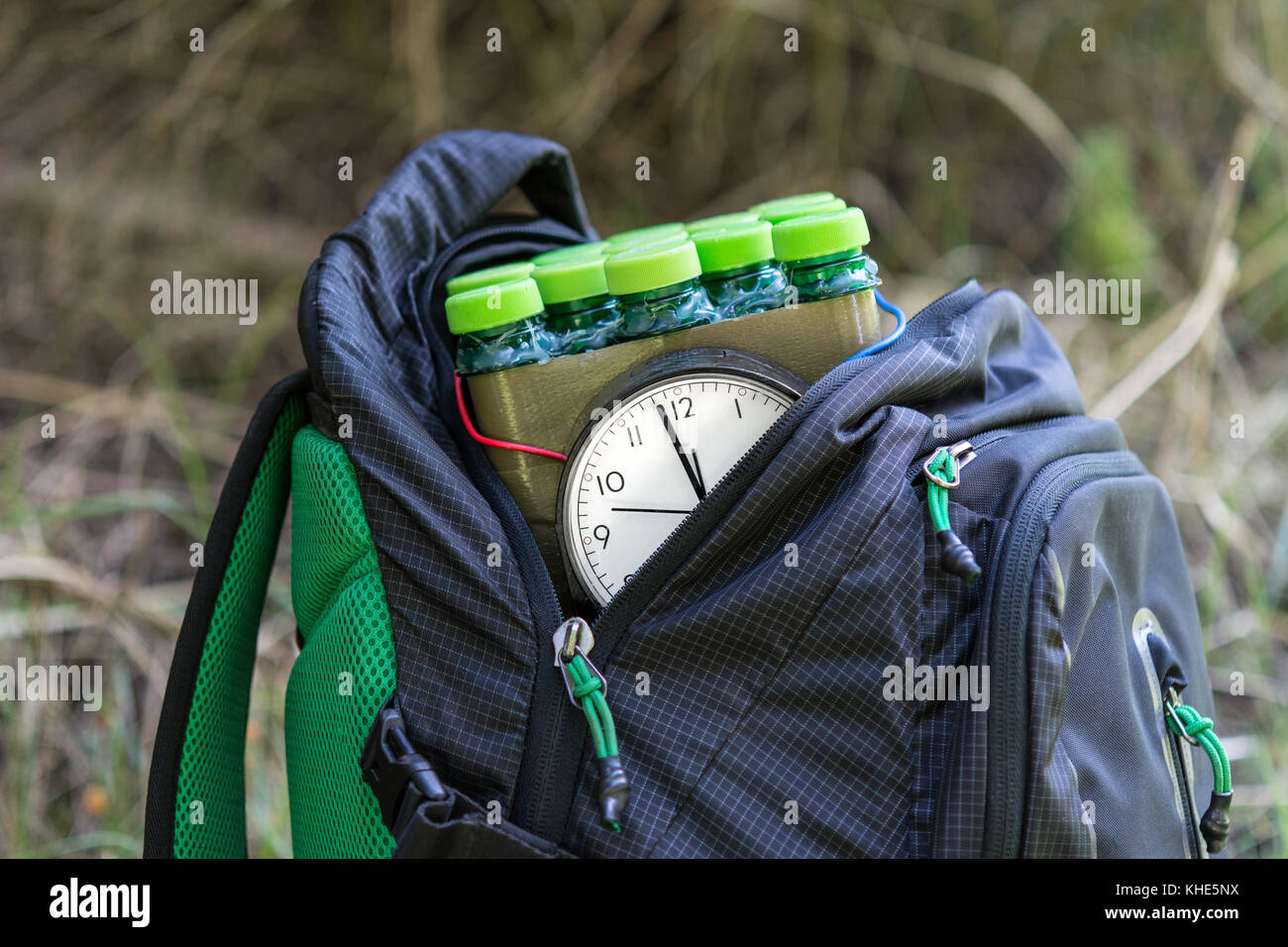 Close-up of timed bomb in the backpack. Dangerous explosive device in pack on grassy background. Stock Photo