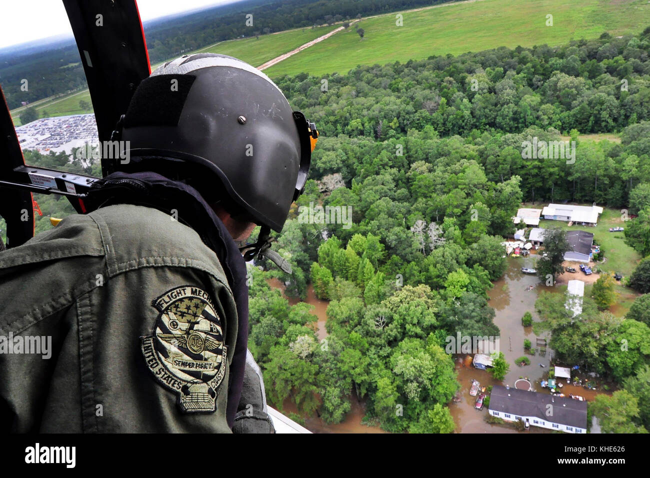 A Coast Guardsman looks out from an MH-65 Dolphin helicopter searching for stranded residents in Baton Rouge, LA on Aug. 15, 2016. The guardsman is an aviation maintenance technician assigned to Air Station New Orleans, LA. Coast Guard photo by Petty Officer 1st Class Melissa Leake Stock Photo