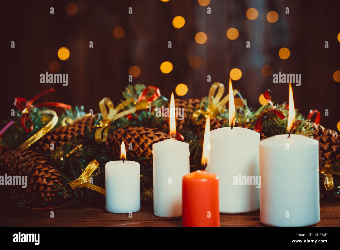 Christmas burning candles on wooden table on the bokeh background of luminous garlands at night. The concept of a family holiday, romantic Stock Photo