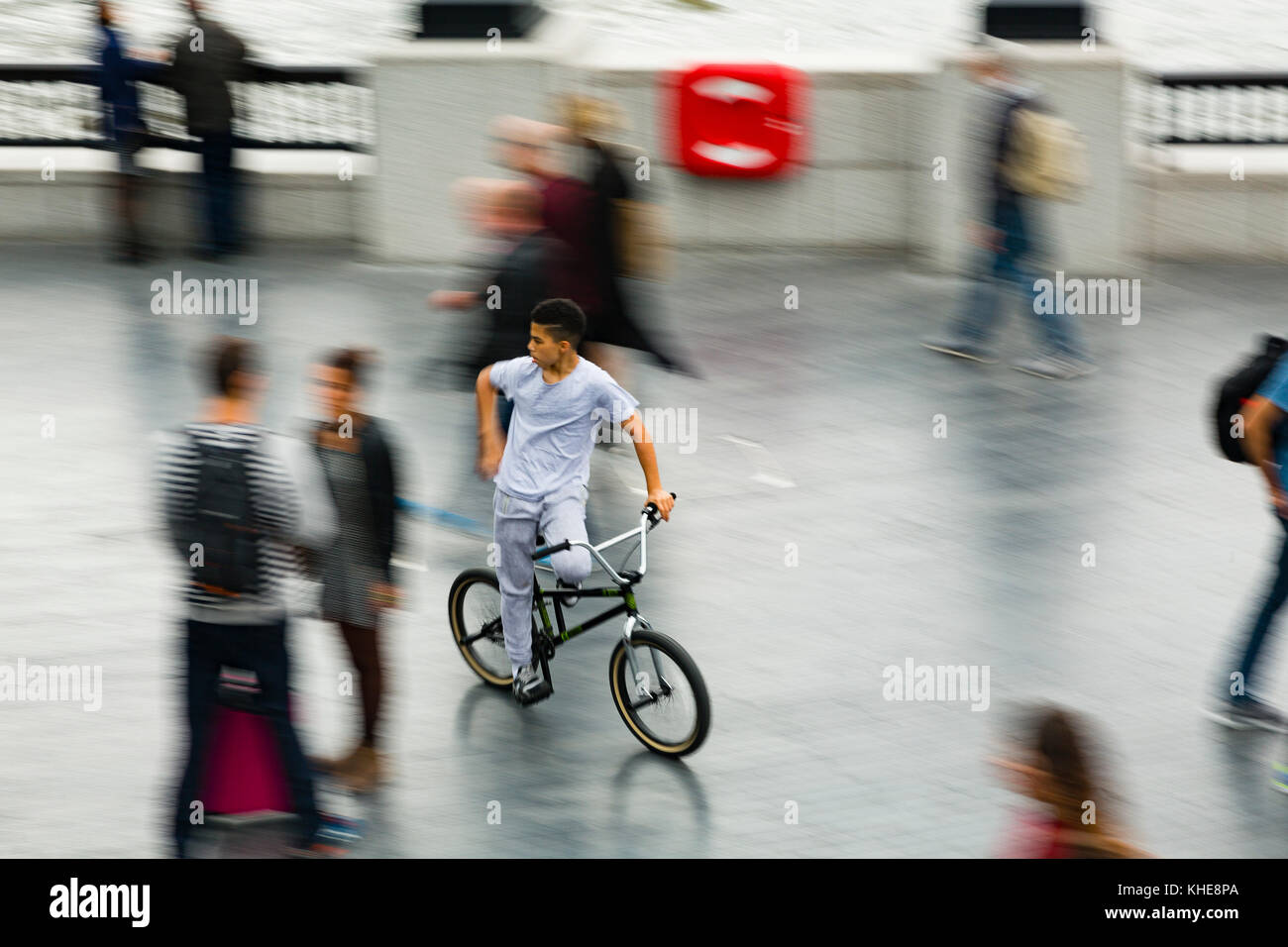 London, UK. A young teenager on a BMX rides through the crowds near City Hall on the south bank of the River Thames. Stock Photo