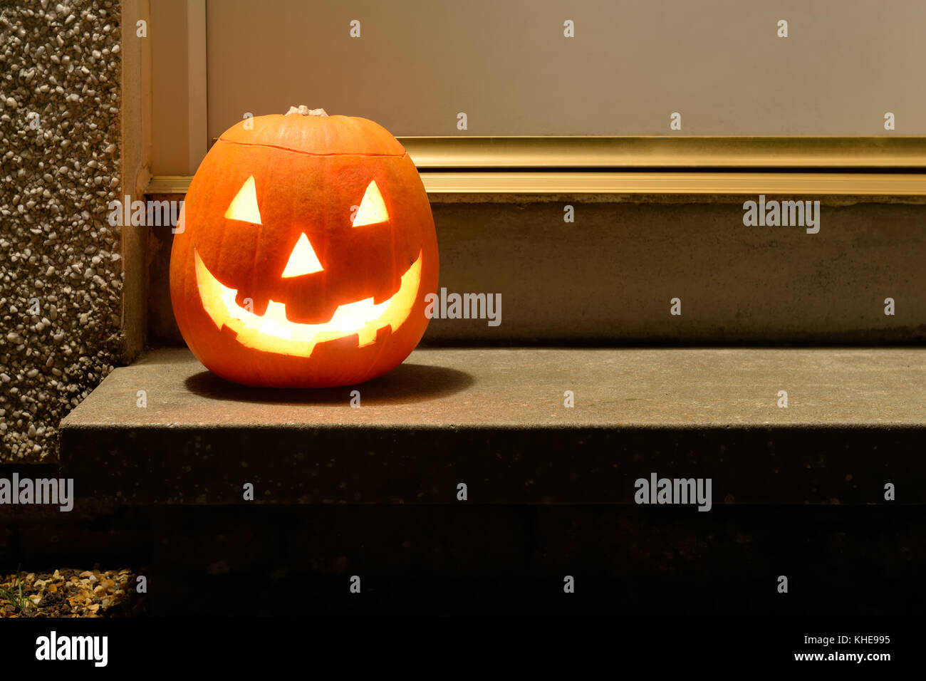 A carved pumpkin with scary face sitting on a doorstep at Halloween in Glasgow, Scotland, UK Stock Photo