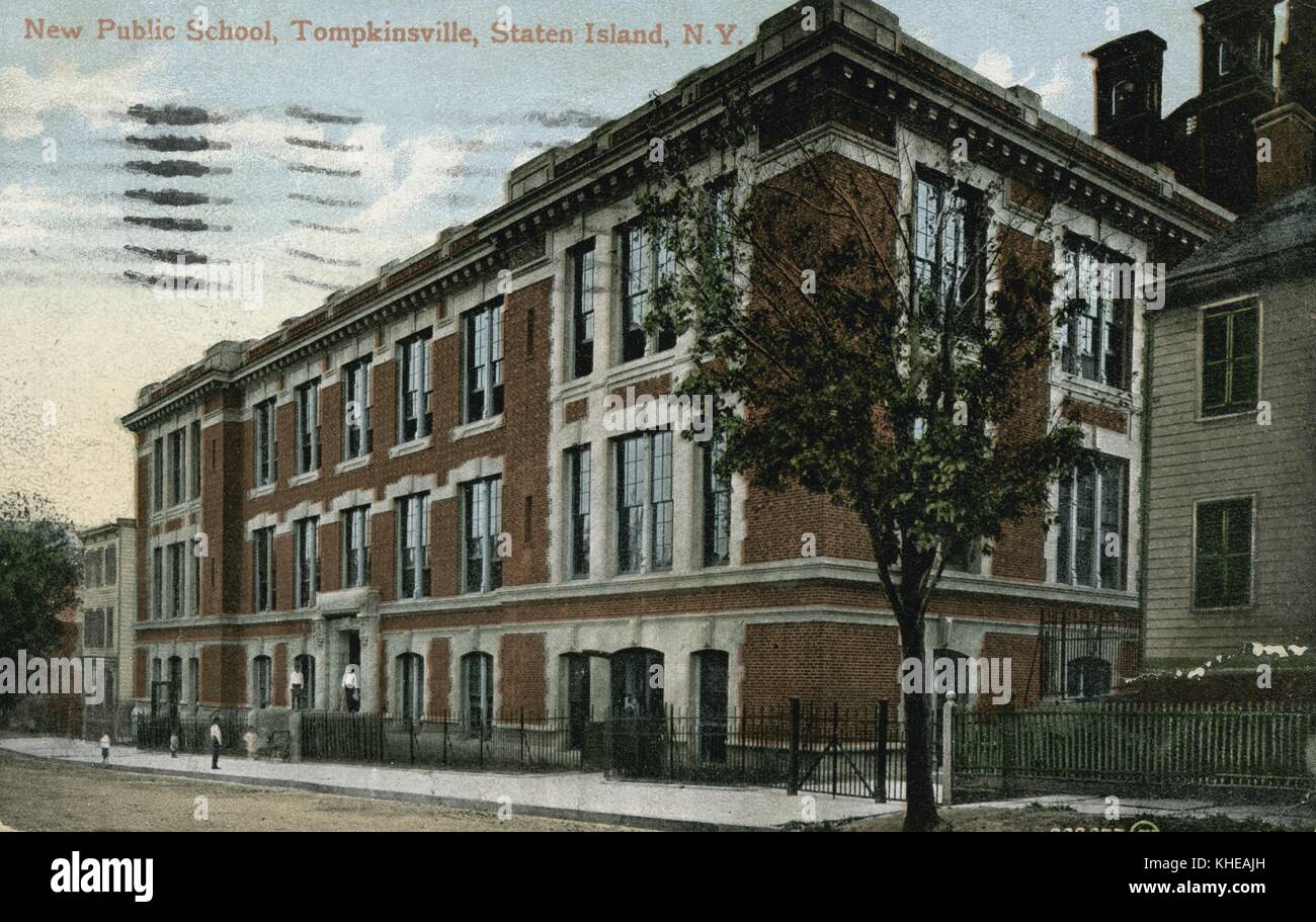 A postcard from a tinted photograph of a then-new public school building in Tompkinsville, the three story structure is composed of brick and large windows, the school is situated between other homes on the same block, students can be seen in uniform outside of the entrance to the building, Staten Island, New York, 1900. From the New York Public Library. Stock Photo