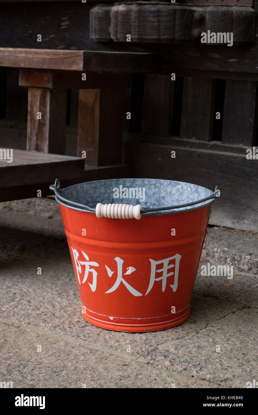Nara, Japan - May 31, 2017: Traditional red fire bucket with water in front of the wooden temple as fire prevention Stock Photo
