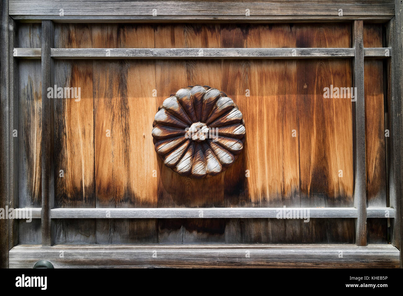 Nagano - Japan, June 3, 2017: Ancient wooden and weathered door with a carved Chrysanthemum at the Zenkoji temple Stock Photo
