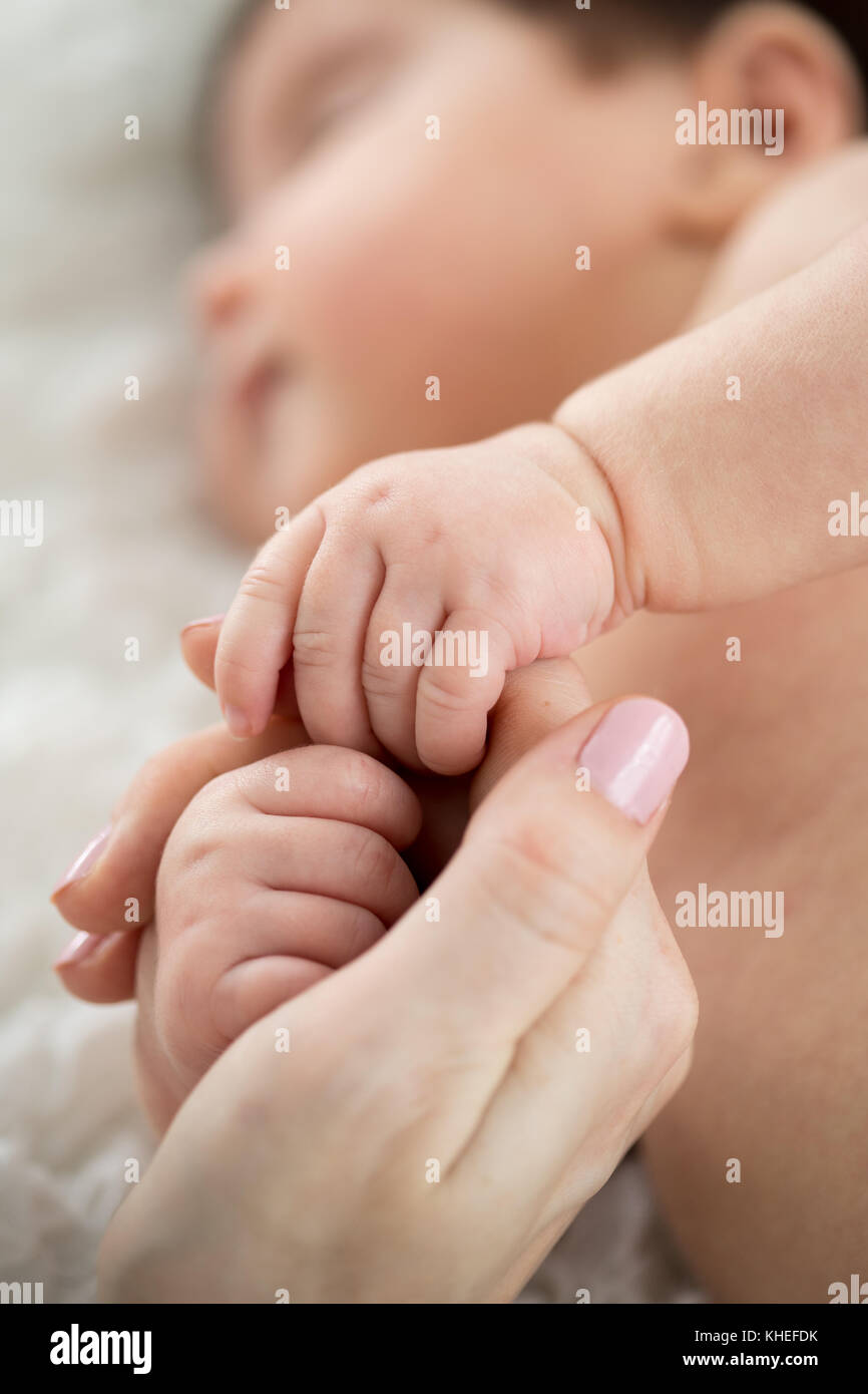 Sleeping baby holding mom's finger. Maternity and childhood concept. Stock Photo
