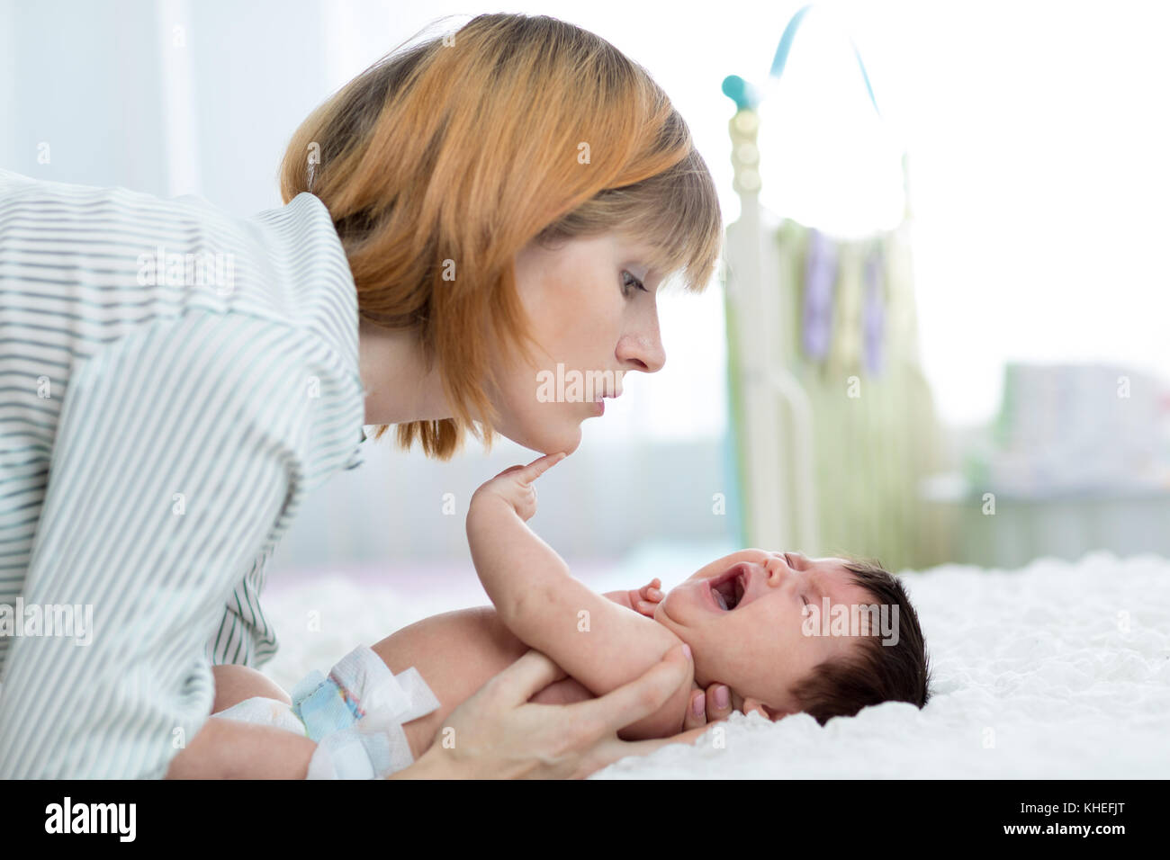 Mother comforts her crying newborn baby at home Stock Photo