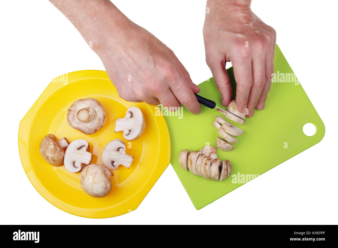 The chief cook of the restaurant with a sharp knife finely chops the mushrooms champignons to make sauce with cream. Isolated on white studio shot Stock Photo