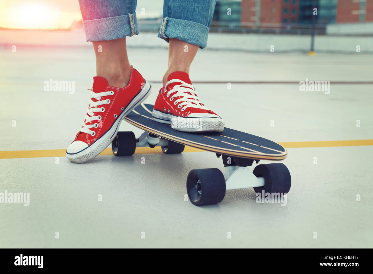 Trendy woman legs in urban style posing on skateboard, closeup, outdoors, cinematic color graded Stock Photo