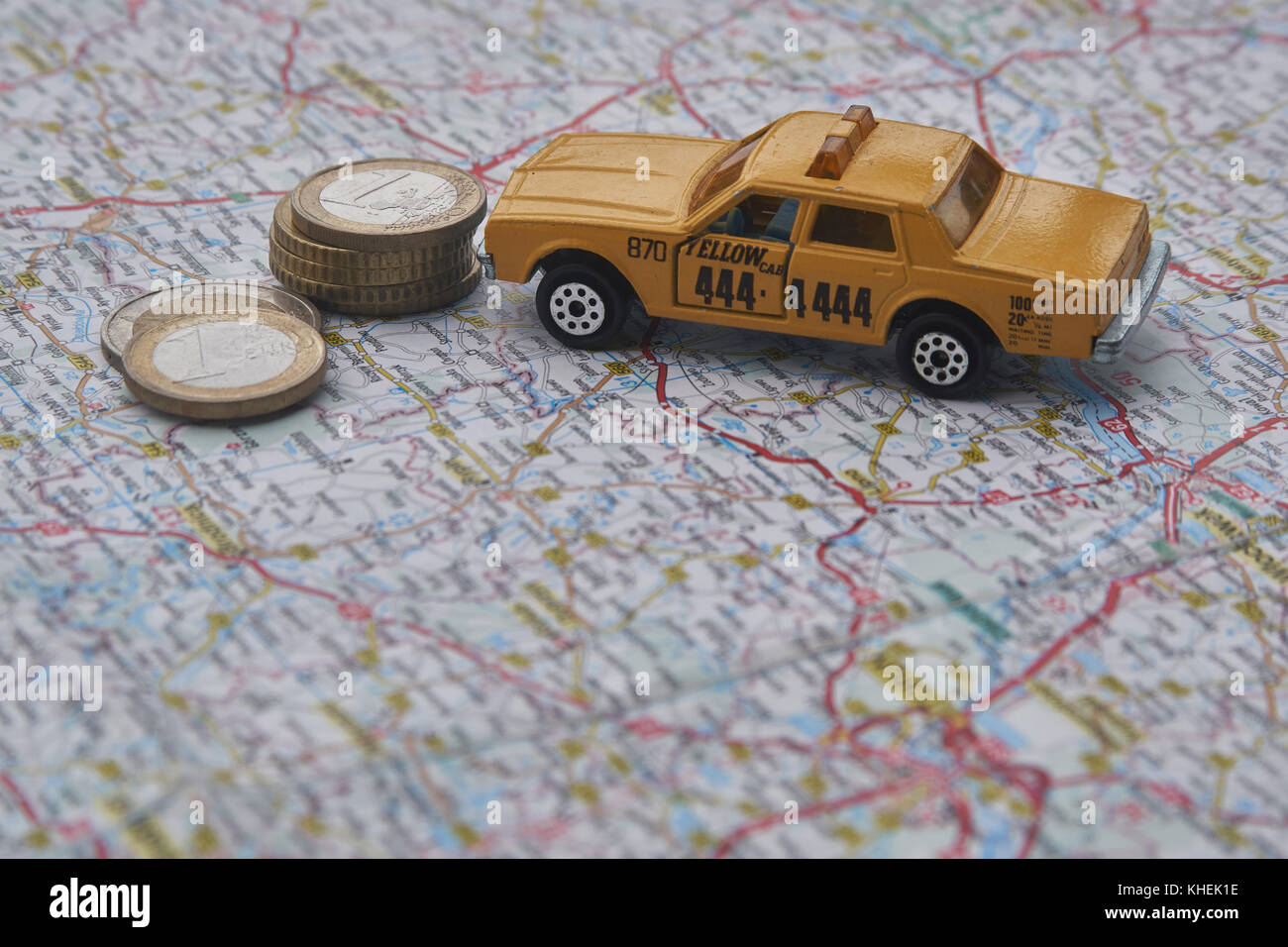 A toy taxi next to some euro coins on a map Stock Photo