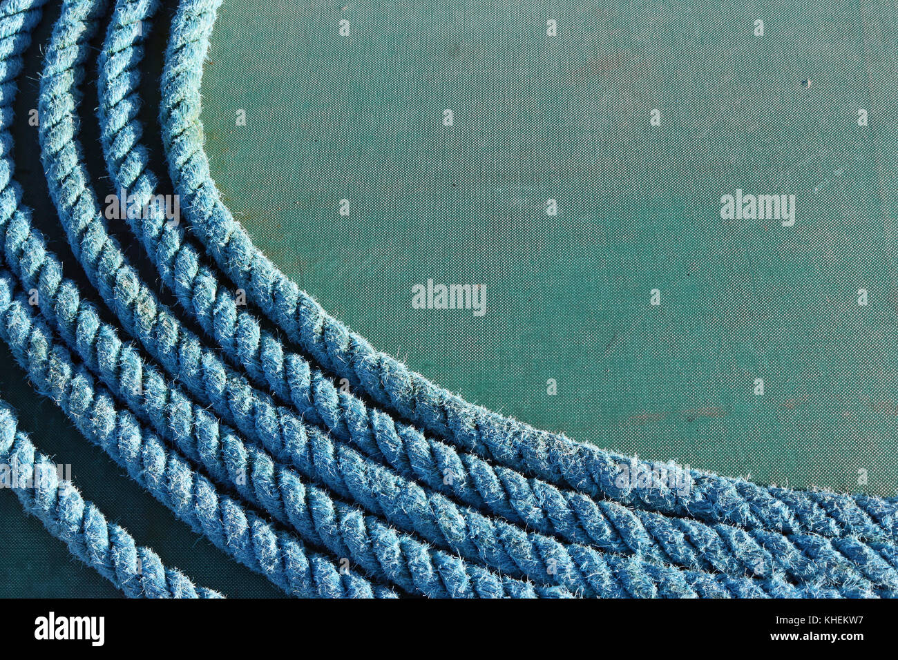 Coiled blue synthetic rope with a background of green tarpaulin on a sailing ship. Good copy space. Stock Photo
