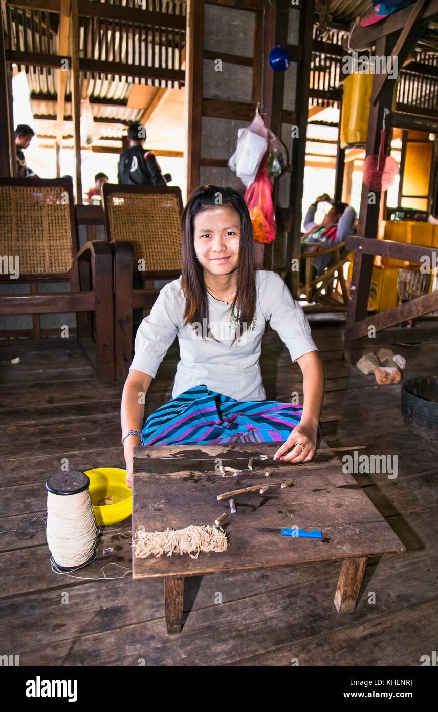 INLE, MYANMAR - MARCH 4 2017: Young burmese woman making thread from lotus flower in a floating village at Inle Lake on March 4, 2017, Myanmar.(Burma) Stock Photo