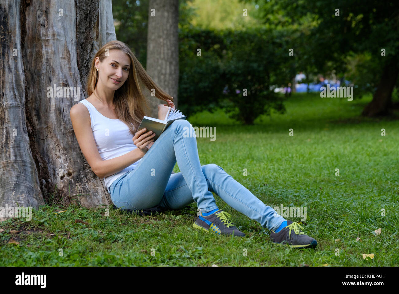 Young woman reading a book in the park Stock Photo - Alamy