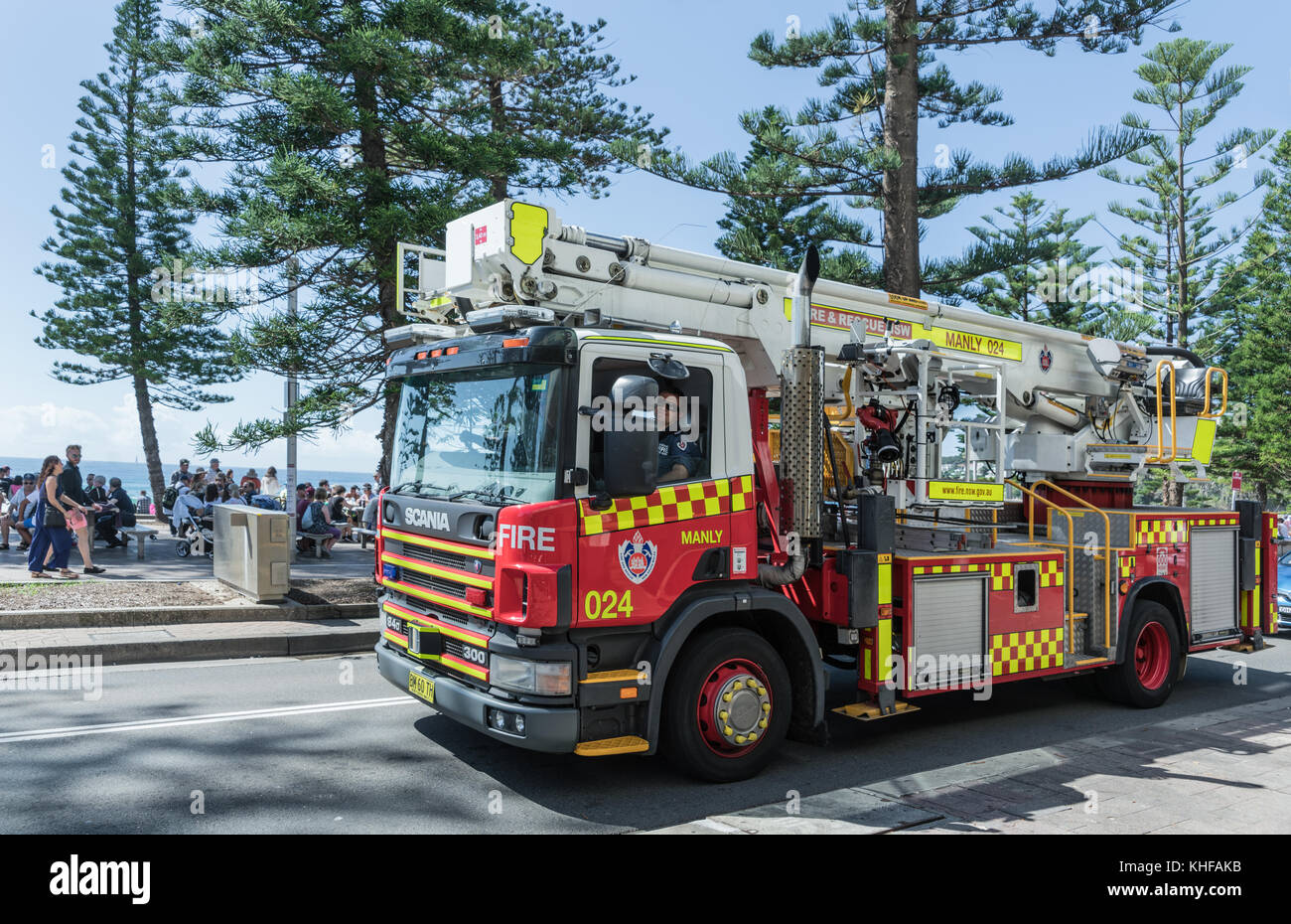 Sydney, Australia - March 26, 2017: Red, yellow and white fire truck with ladder and pump motors on South Steyne along boardwalk. Green trees and peop Stock Photo