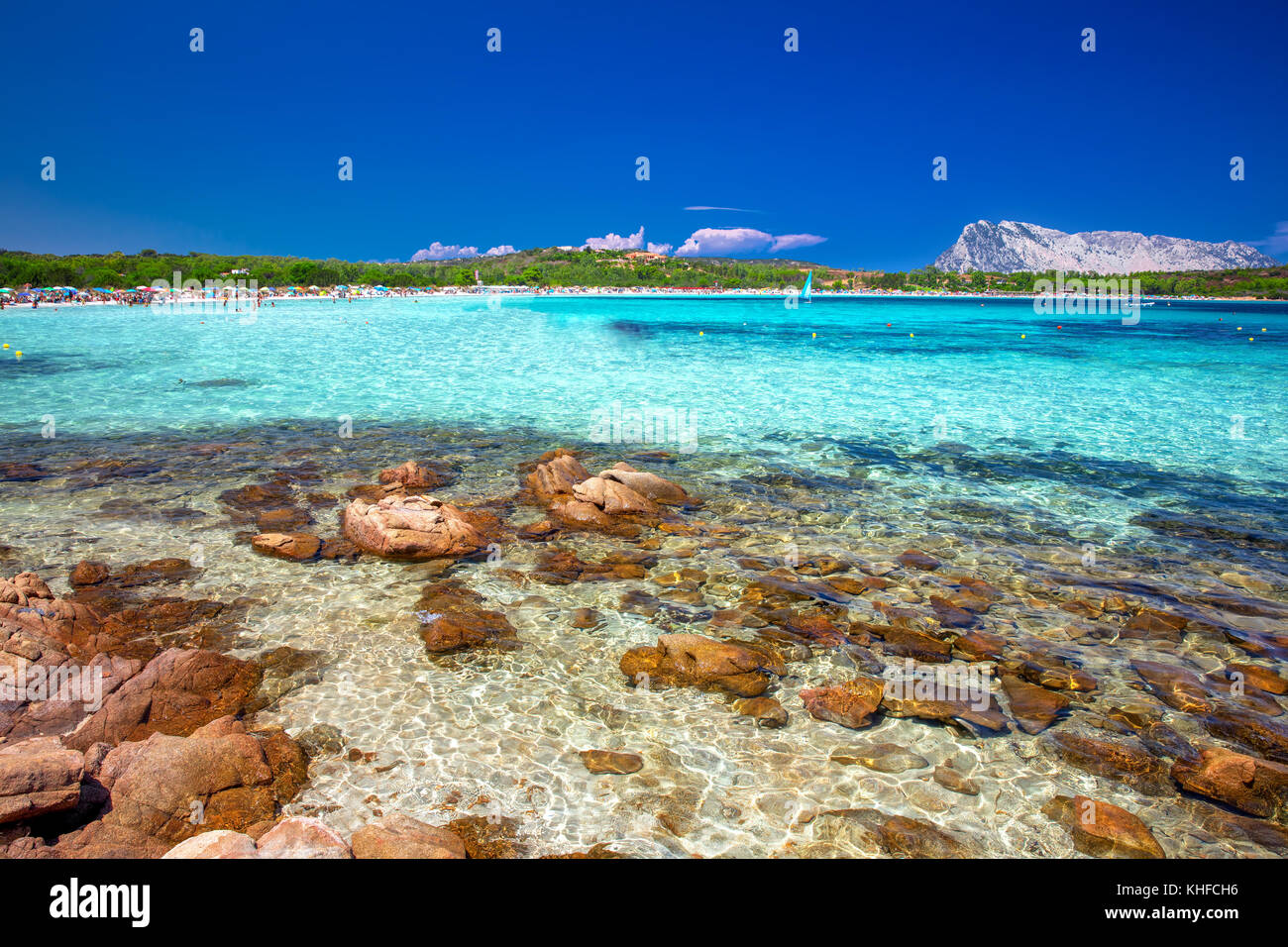 Cala Brandinchi beach with Isola Travolara in the background, red stones and azure clear water, Sardinia, Italy Stock Photo