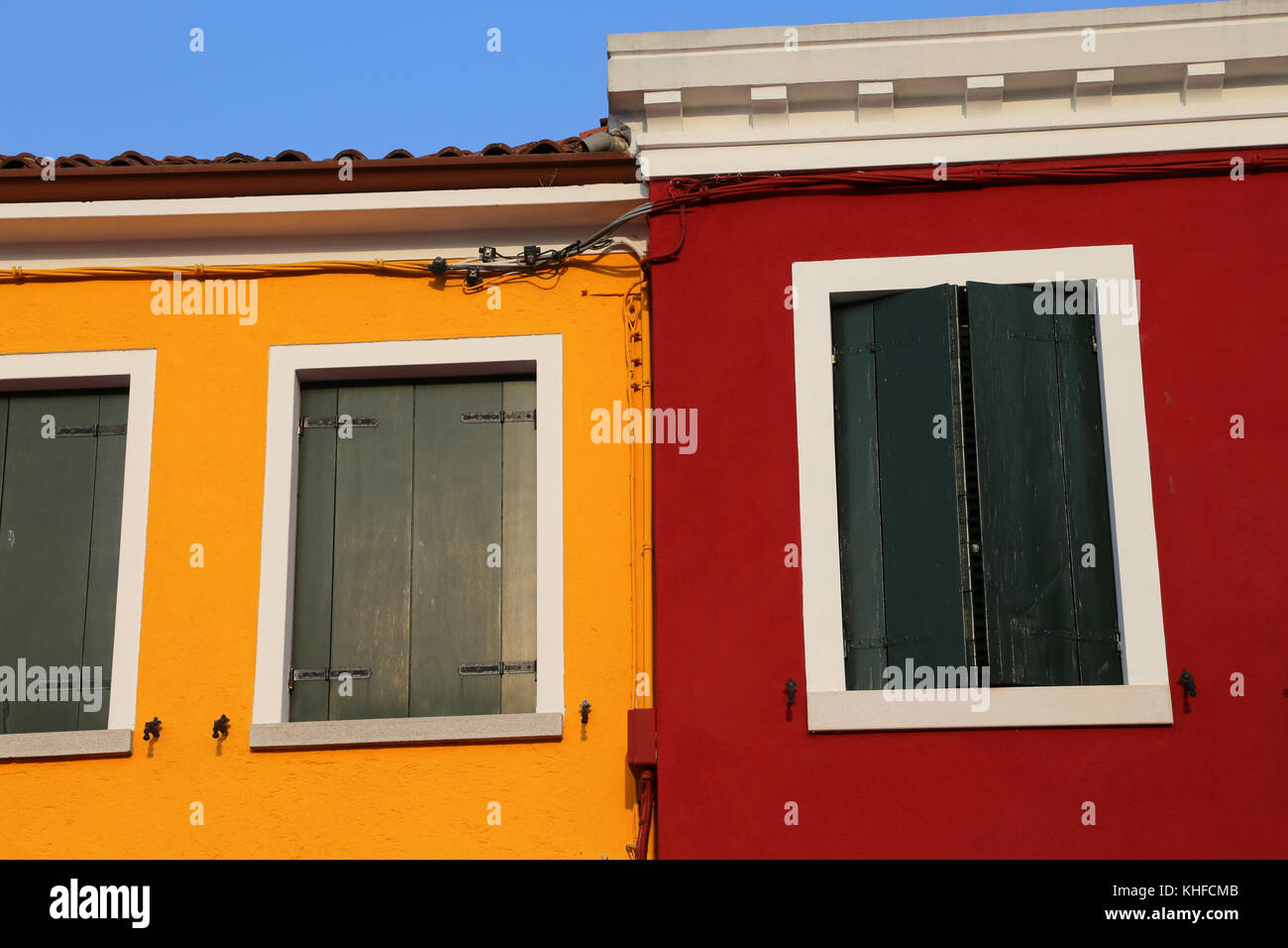 house detail with painted yellow and red wall and closed windows Stock Photo