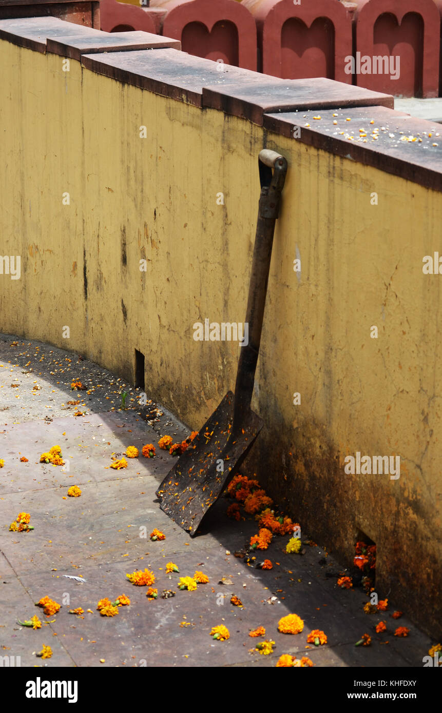 Flower petals and shovel leaning against wall in New Delhi India Stock Photo