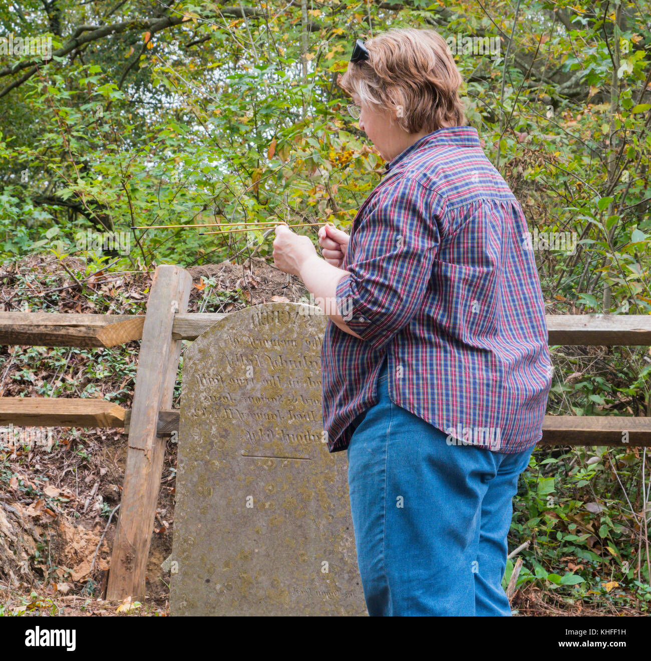 Woman using dowsing rods in rural US Appalachian graveyard Stock Photo