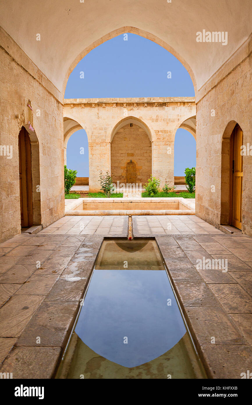 Ancient theological school known as Zinciriye Madrasah and reflection in its shallow pool in its courtyard, in Mardin, Turkey Stock Photo