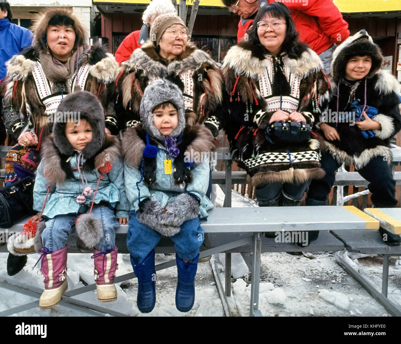 A native Alaskan grandmother shares spectator seats with her daughters and their children in their fur-decorated parkas to watch the World Championship Sled Dog Races in Anchorage that take place during the Anchorage Fur Rendezvous, the oldest and largest winter festival in Alaska, USA. Dog teams and their mushers compete over three days to determine the winner with the fastest elapsed time. The event began in 1946 and is considered the grandfather of all Alaska races. Stock Photo