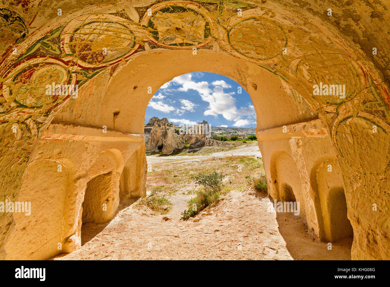 Rock cut church and its frescos with a view over the volcanic formations in the background, in Cappadocia, Turkey. Stock Photo