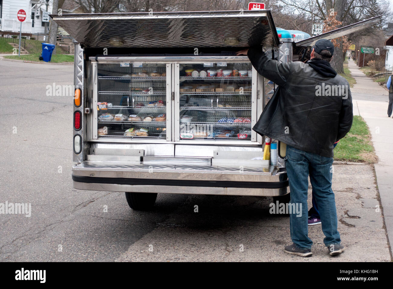 Man raising cover to a mobile lunch truck stuffed full of sandwiches and other goodies in front of a business. St Paul Minnesota MN USA Stock Photo