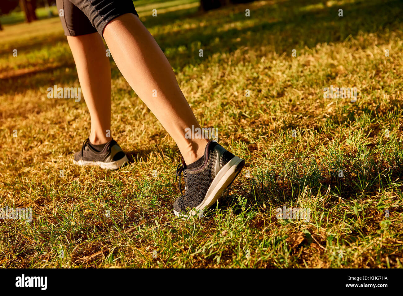 Close up of the legs of a young woman who is running off road in a park