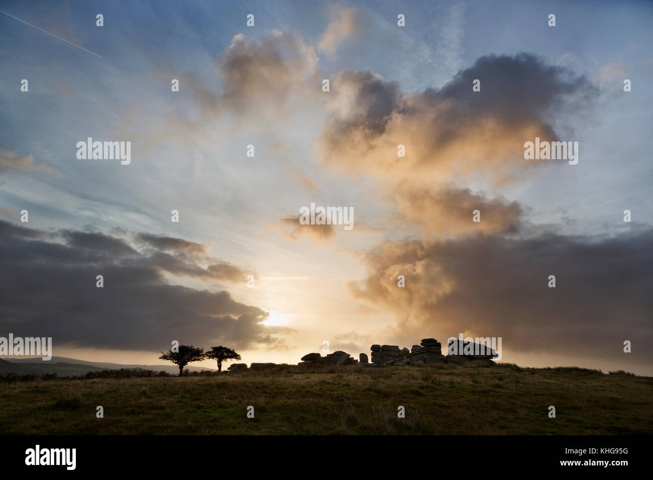 Combestone Tor on Dartmoor silhouetted against a dramatic sky at sunrise Stock Photo