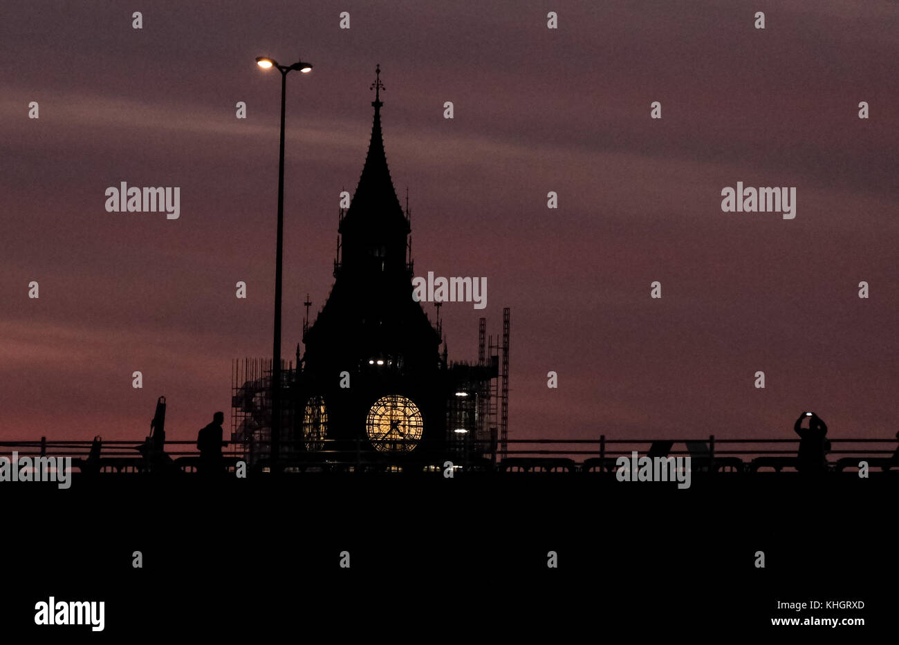 Friday 17th November 2017. London England. London is greeted with a wonderful sunset to mark the end of Friday as commuters come out of work and stop to photograph the spectacle. The gent to right frames Elizabeth Tower( Big Ben) and snaps a picture on his mobile phone as the the clock face peeks out from the scaffolding surrounding the tower. Paul Watts/ Alamy live news Stock Photo