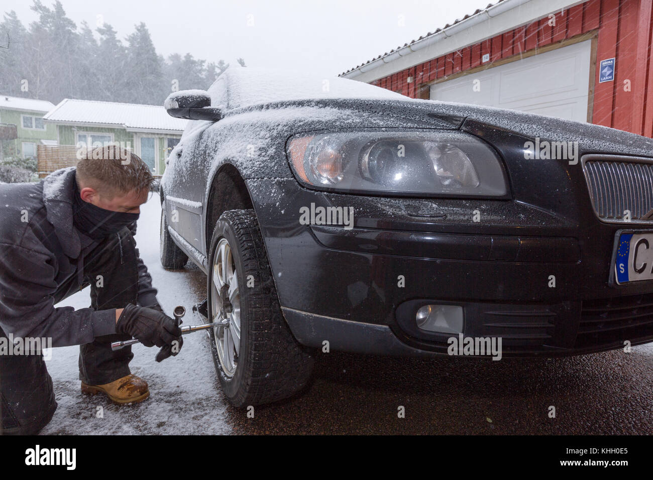 Man changing car tires to snow tires outdoors during snowfall   Floda just outside Gothenburg, Sweden. 19th November, 2017. First blizzard and heavy snowfall of the season causes treacherous road conditions for motorists as the date for mandatory winter tires have not yet come into effect. Martin Carlsson/Alamy Live News Stock Photo