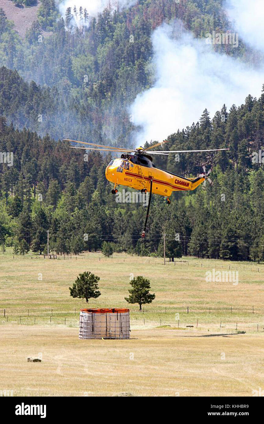 A helicopter fills its water bucket at mobile water station to use against the Crow Peak Fire. The Crow Peak Fire located in the Black Hills National Forest near Spearfish, SD began on Jun. 24, 2016 started by lightning.  The Crow Peak Fire has consumed 1,350 acres. U.S. Forest Service photo. Stock Photo