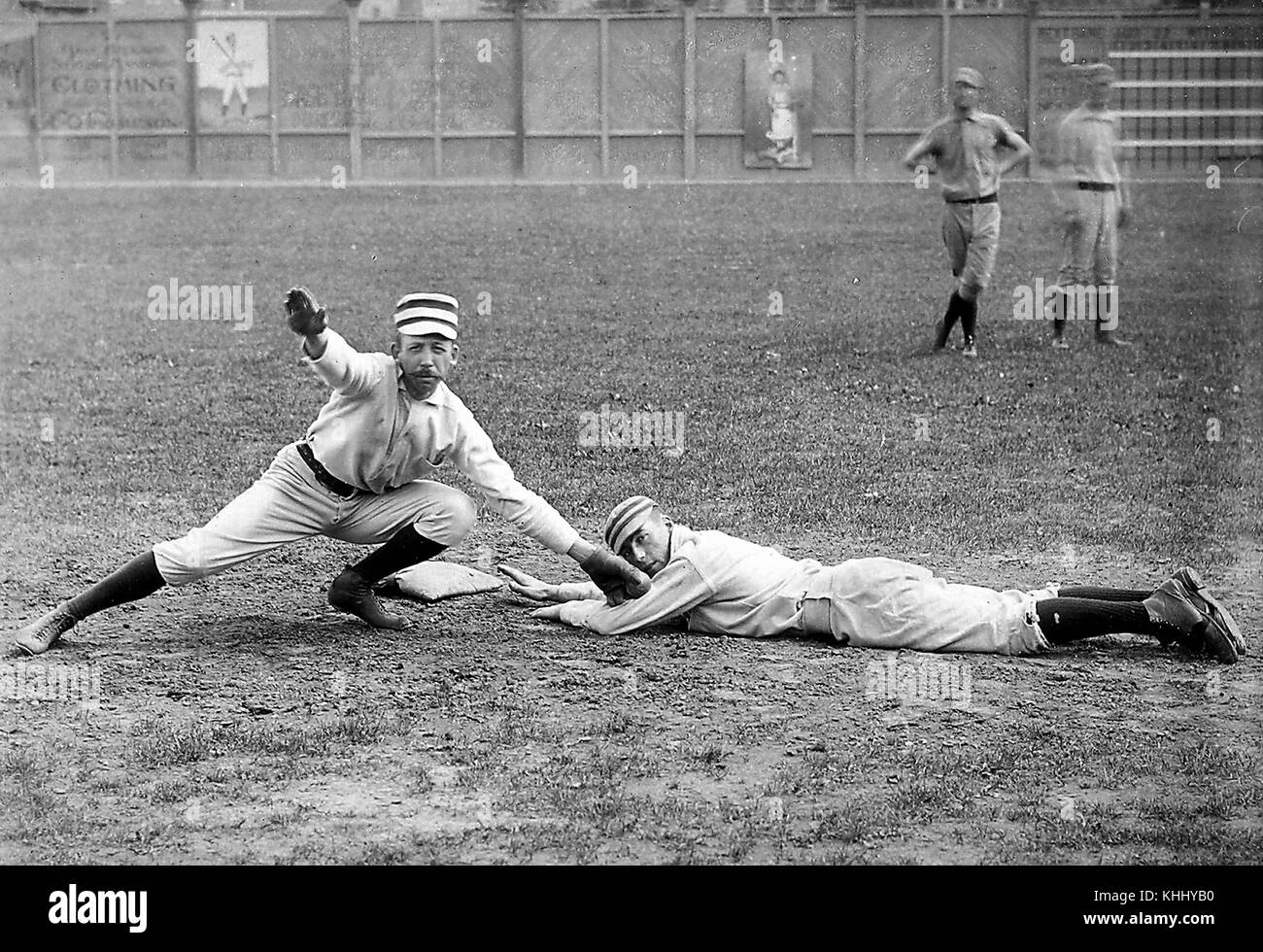 A photographic portrait of two baseball players from the Philadelphia Quakers, Arthur Irwin is pretending to tag out Tommy McCarthy who is pretending to be sliding headfirst in to a base, 1900. From the New York Public Library. Stock Photo