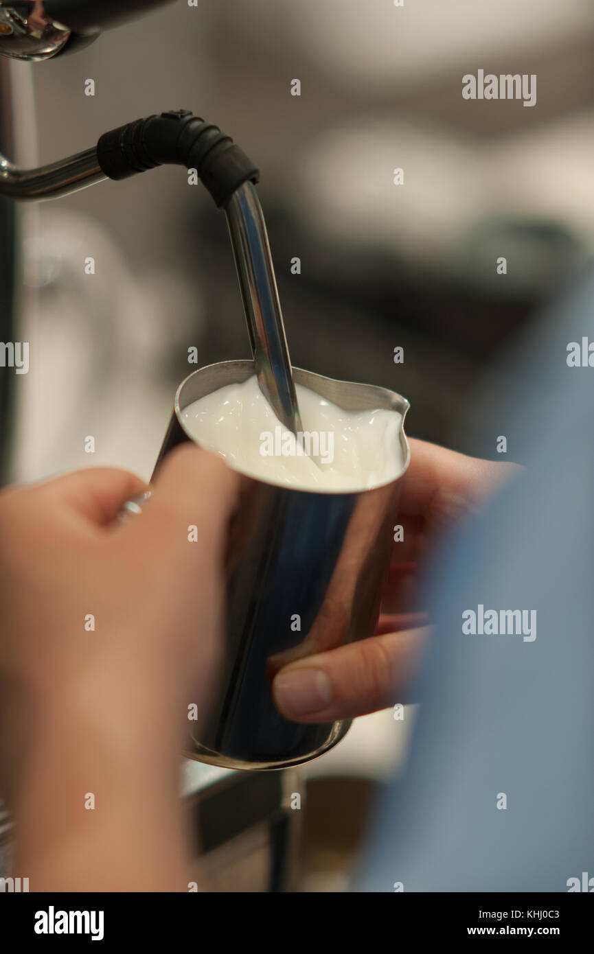 A barista steaming milk for a coffee. Stock Photo