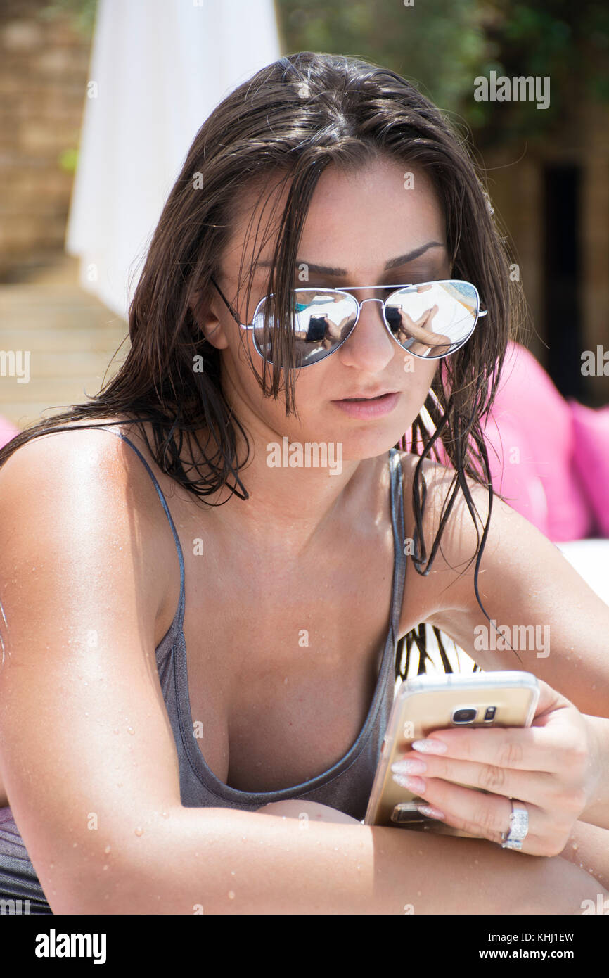 Beautiful young woman in bikini hand holding mobile phone by the pool Stock Photo