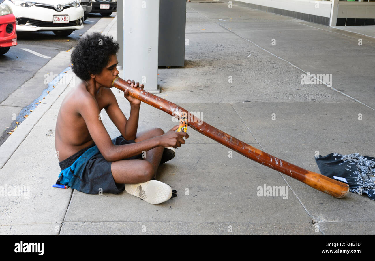 Young Aboriginal Boy playing the didgeridoo and busking in the street, Cairns, Far North Queensland, FNQ, QLD, Australia Stock Photo