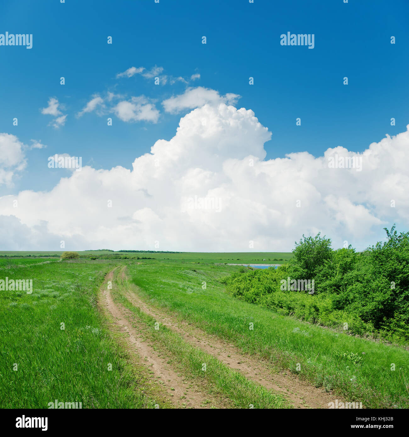 dirty road in green landscape and clouds over it Stock Photo - Alamy