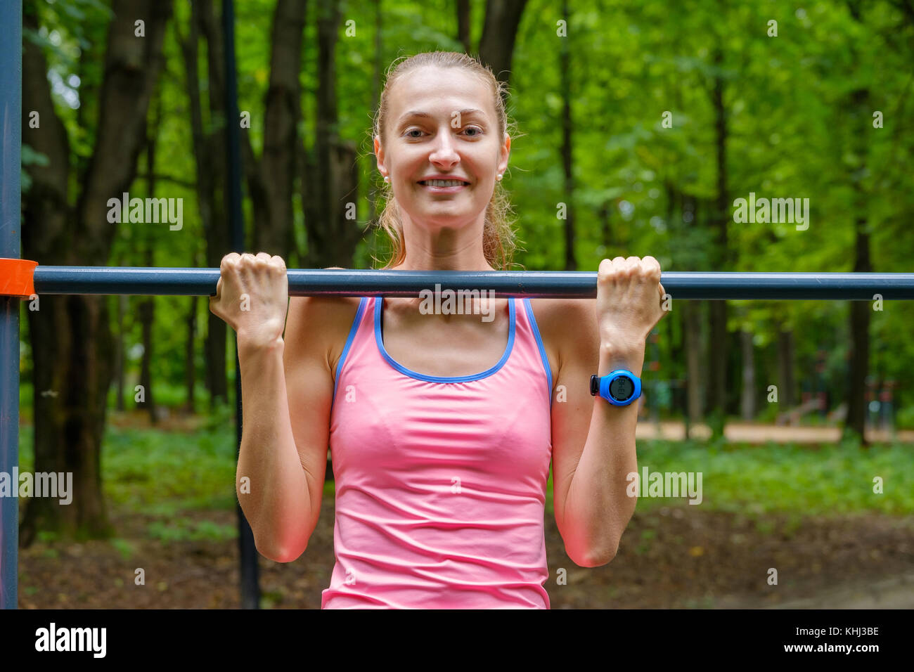 Young slim woman pulls on horizontal bar Stock Photo - Alamy