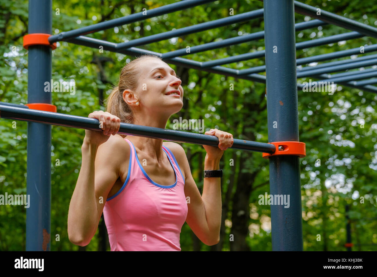 Young slim woman pulls on horizontal bar Stock Photo - Alamy