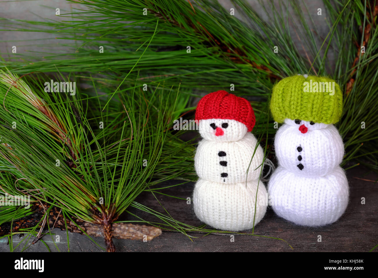 two Christmas snowman from knitted toy standing front of pine Stock Photo